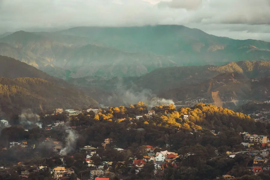 Fog rolling over the pine-covered mountains of Baguio at golden hour