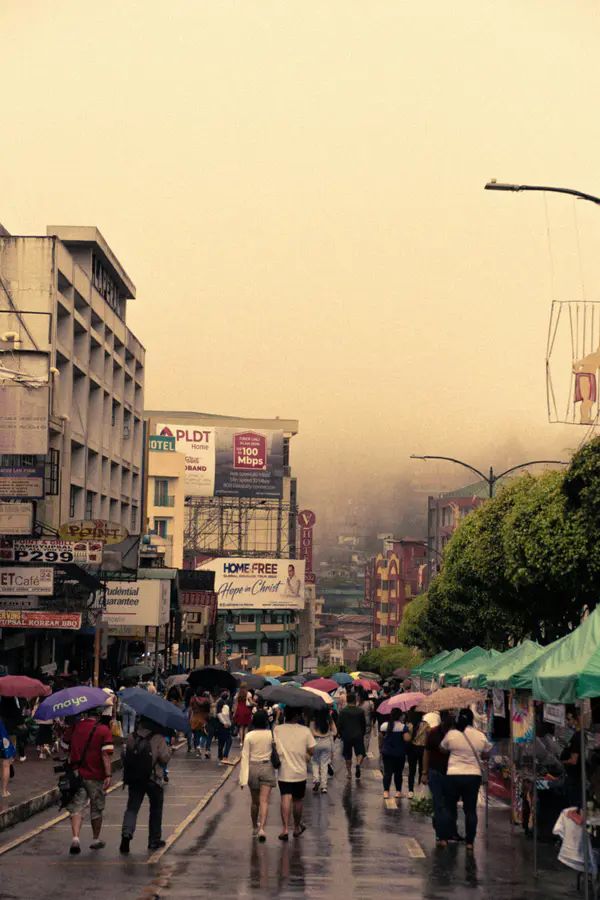 People with umbrellas walking along Session Road in Baguio