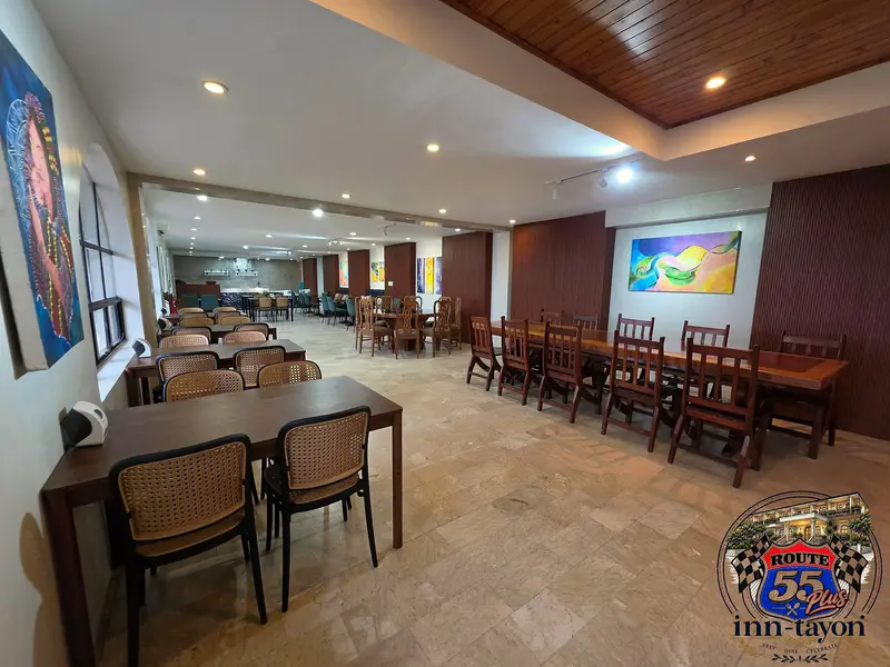 Long dining tables set up in Inn-tayon's hall, with colorful paintings on the walls