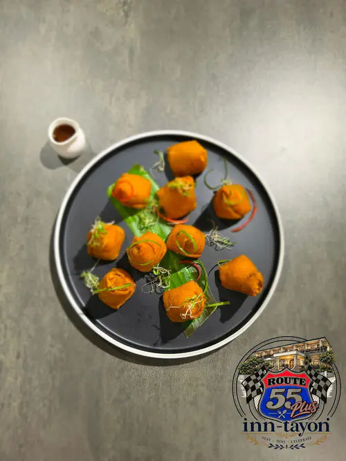 Golden fried bites arranged on a round plate with a small cup of dipping sauce