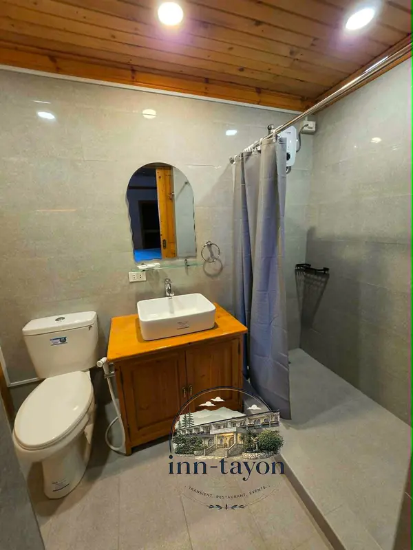 A clean tiled bathroom with a wooden vanity, vessel sink and shower