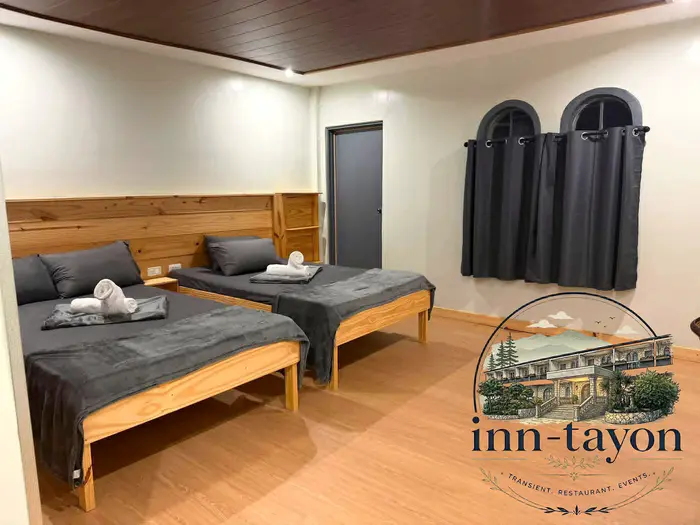 Triple Room with a double bed and a single bed, grey linens and arched windows with dark curtains